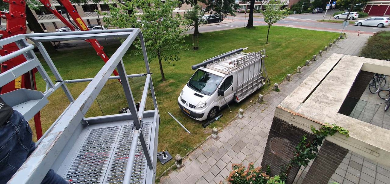 Werkbak en glaswagen tijdens glasplaatsing op verdieping