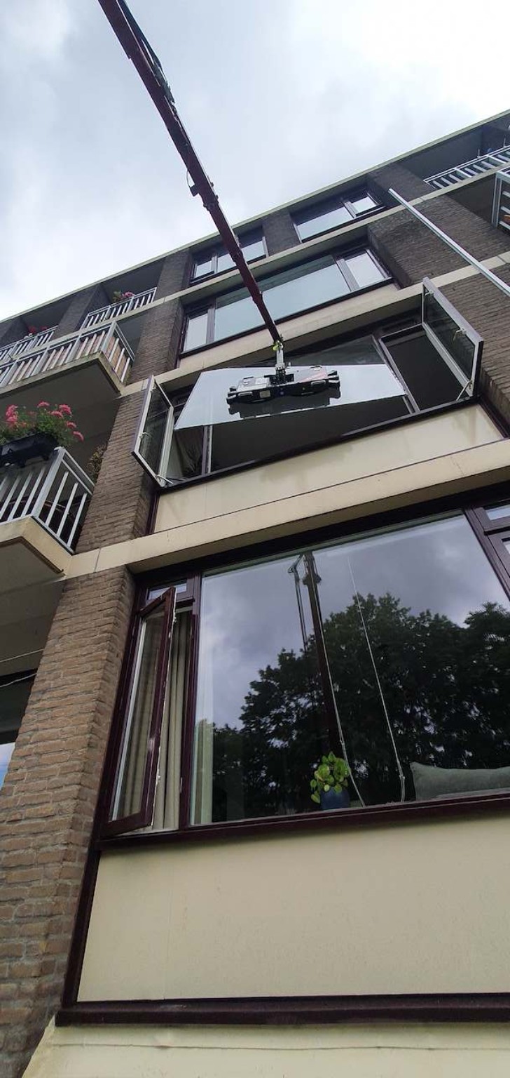 Grote ruit wordt met een kraan naar een appartement gehesen