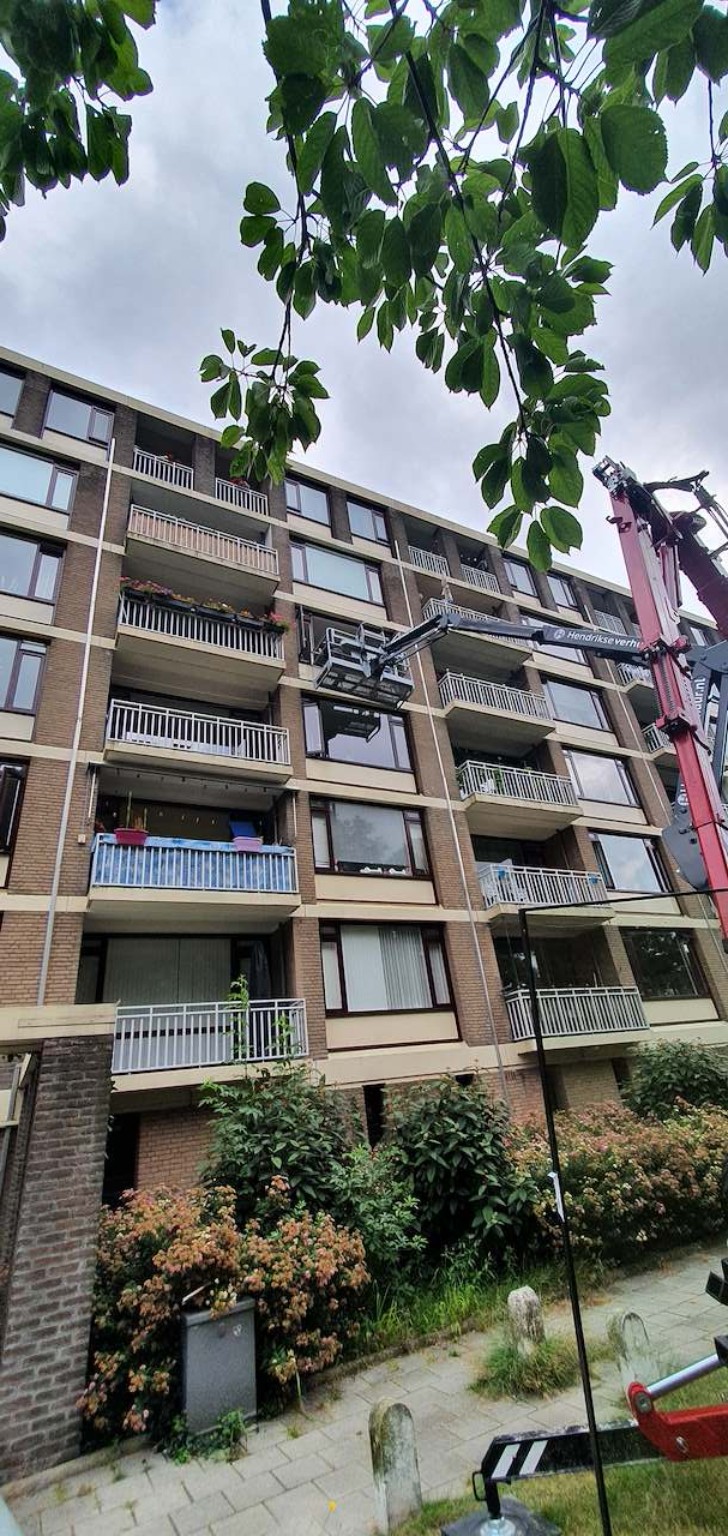 Glasvervanging bij een appartementencomplex met kraan en hoogwerker