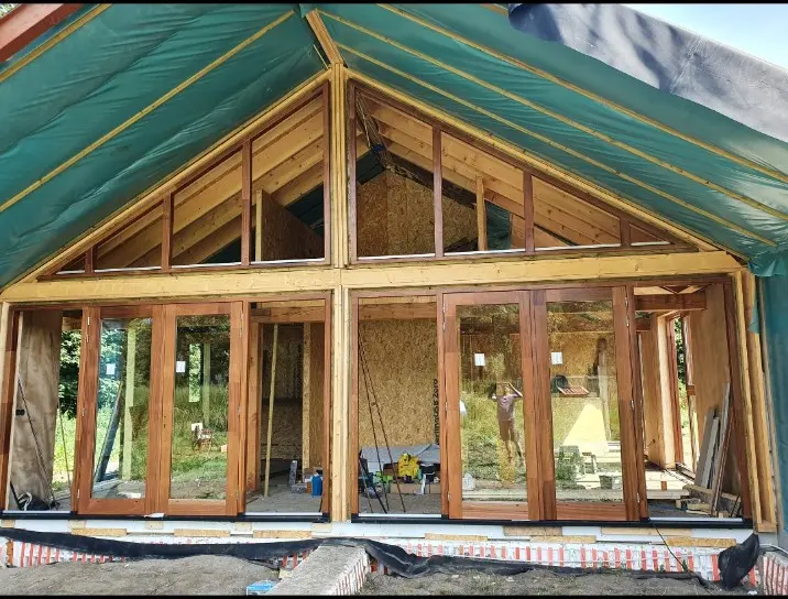 Houten glasgevel met deuren in een woning in aanbouw